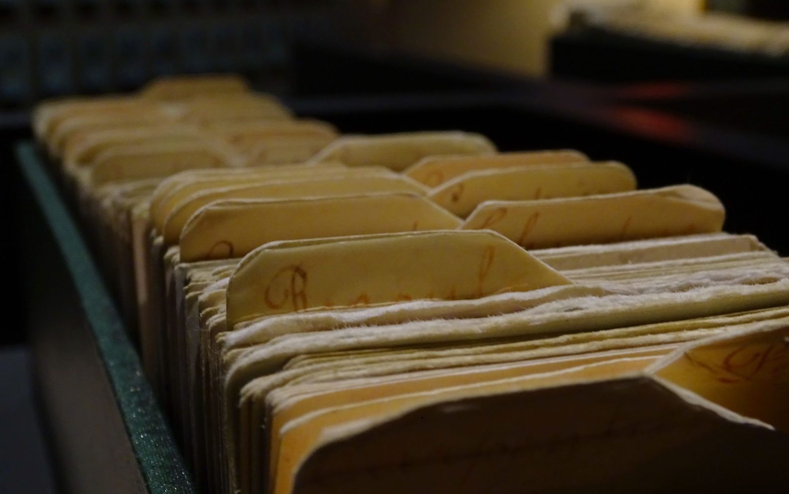 Fichas de archivo antiguas ordenadas en fila dentro de un cajón