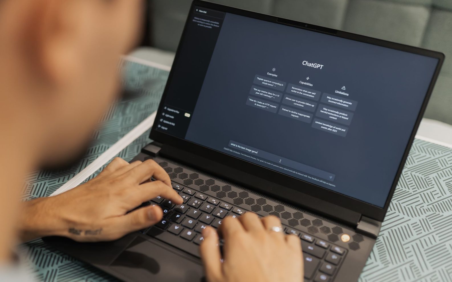 Una persona escribe en una laptop que muestra un asistente de inteligencia artificial