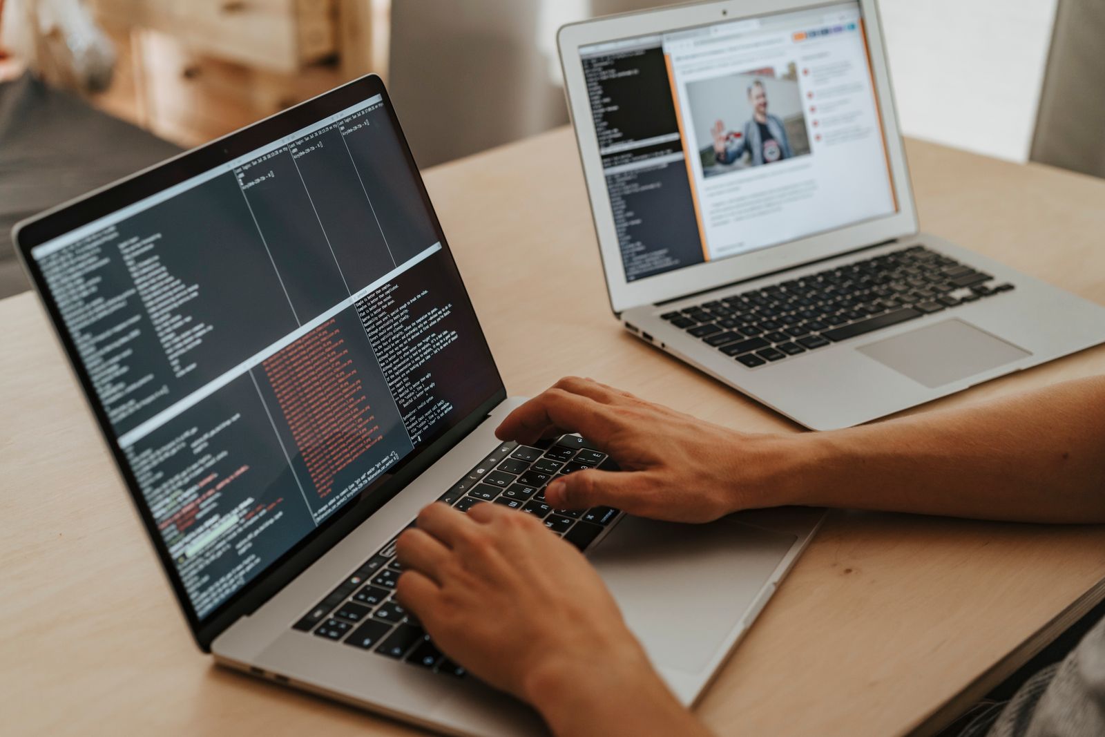 Persona programando en una laptop, con una segunda laptop abierta al fondo