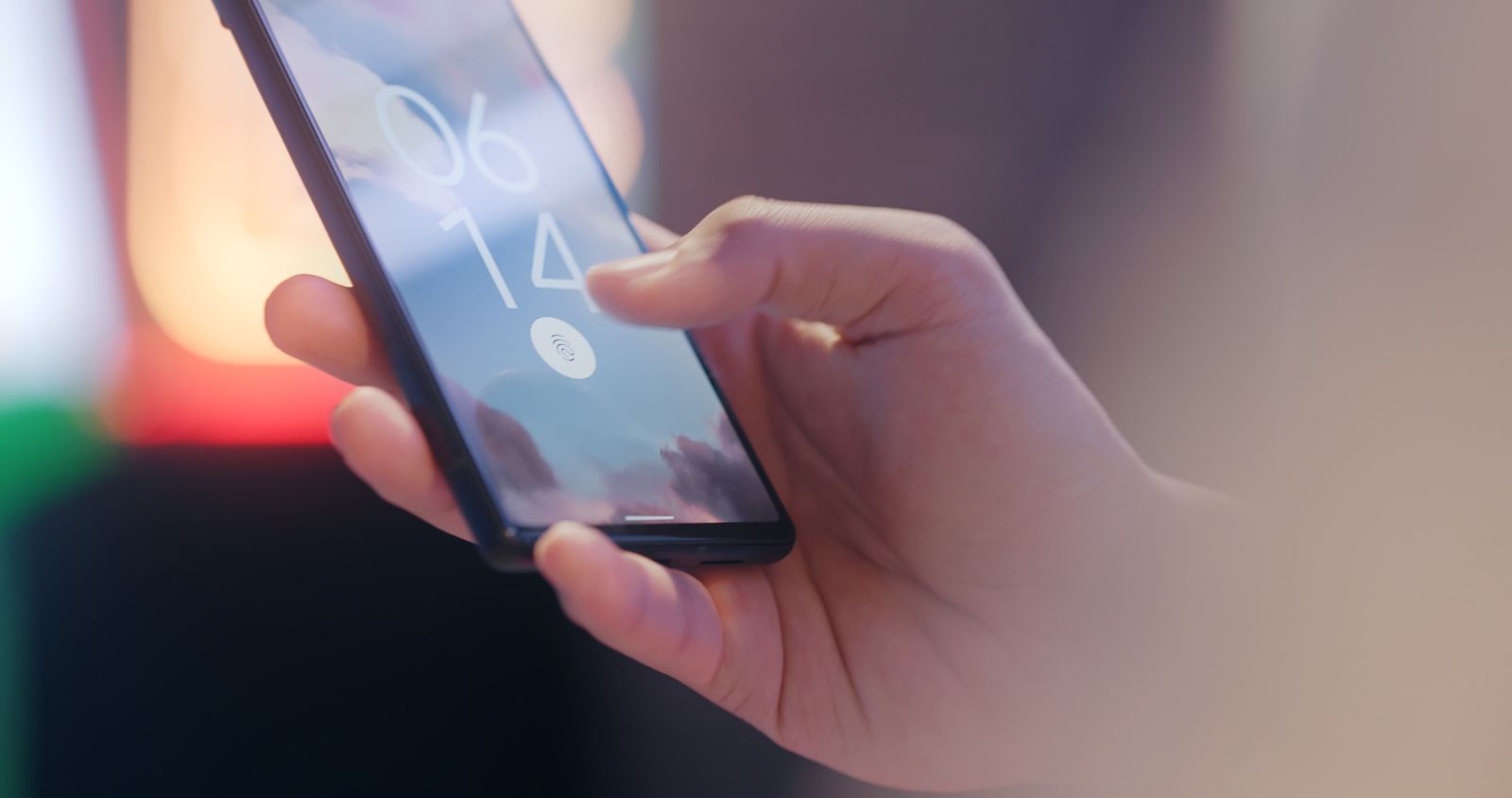 Mano sosteniendo un teléfono con el sensor de huella en la pantalla de bloqueo