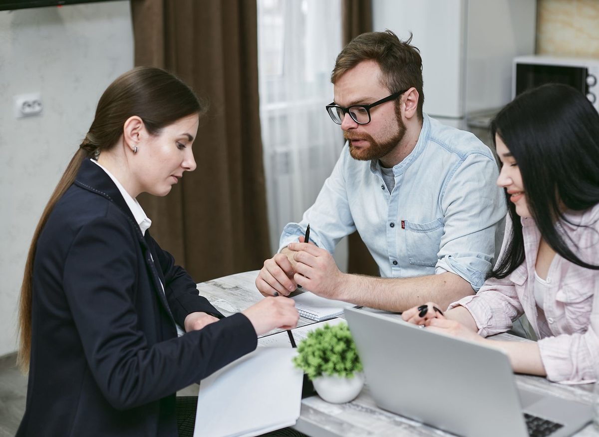 Profesionales conversan alrededor de una laptop durante una reunión de consultoría