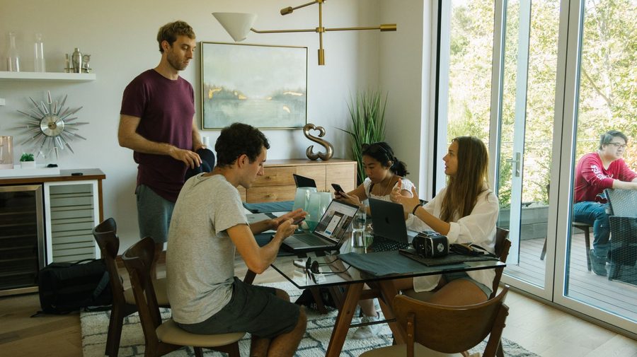 Equipo joven de una startup trabajando con laptops alrededor de una mesa