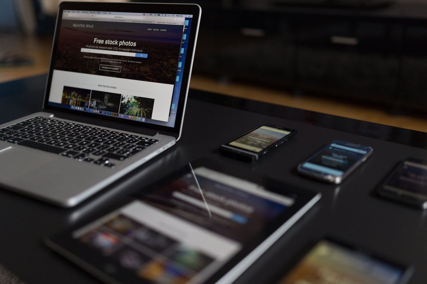 Laptop, tableta y celulares mostrando el mismo sitio web sobre una mesa oscura